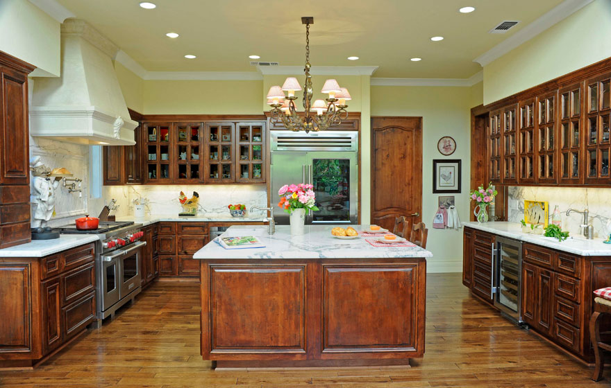 French Lite upper cabinets dazzle this kitchen where the rustic hand-distressed cabinetry contrasts the elegant marble countertops.