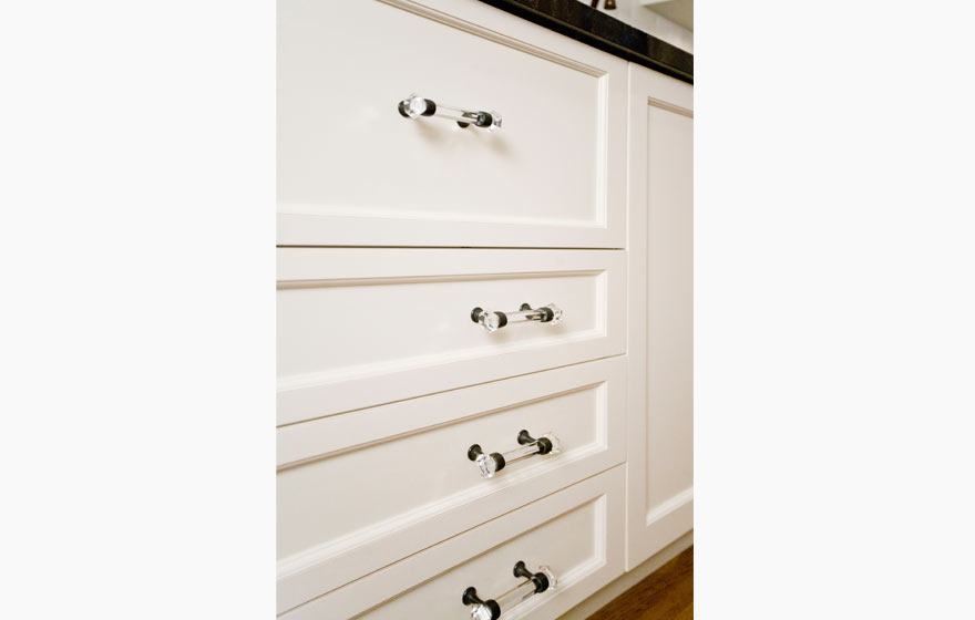 Glass upper cabinets allow cabinetry to extend to the ceiling and add ample storage to this open space.