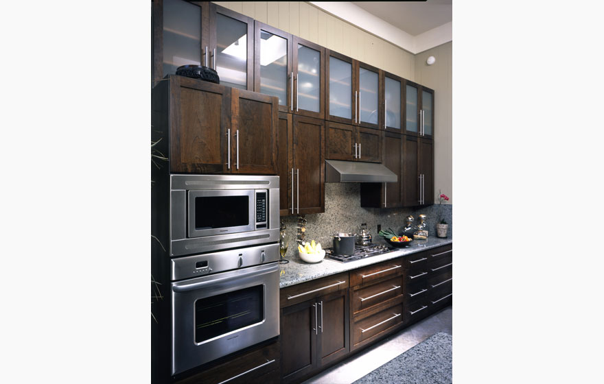 Simple, clean lines translate to a bold sophistication and tall upper cabinetry with glass doors makes a small space appear grand.