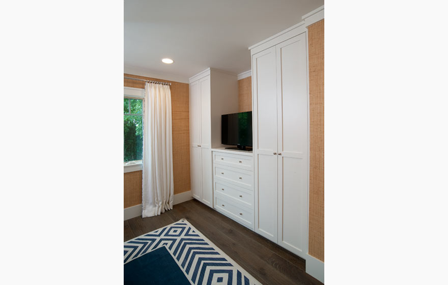 Built-in closet cabinets in this guest room provide ample space for hanging clothes and storage while maintaining a simple, clean appearance.