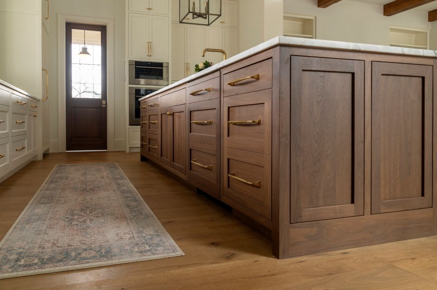 Kitchen island in rich walnut select is accented by painted cabinetry for a warm, eye-catching aesthetic.